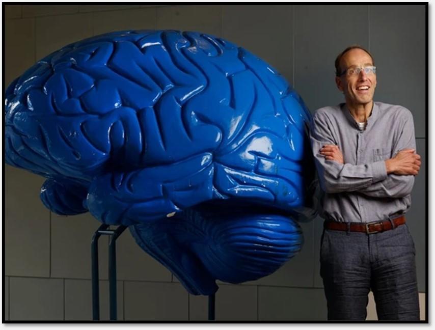 Dr. Georg Northoff standing beside large blue statue of human brain