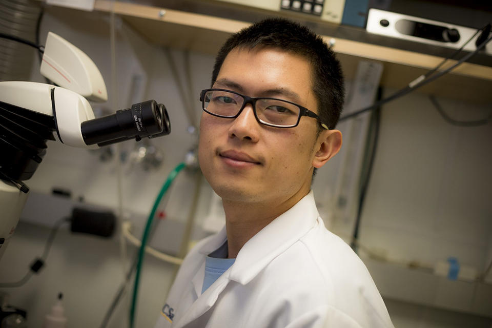 Dr. Simon Chen beside a microscope.