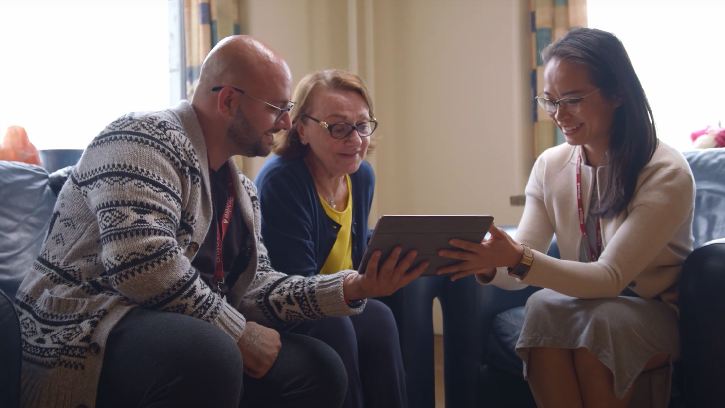 Dr. Amy Hsu smiling and showing information on an iPad to a woman and her adult son.