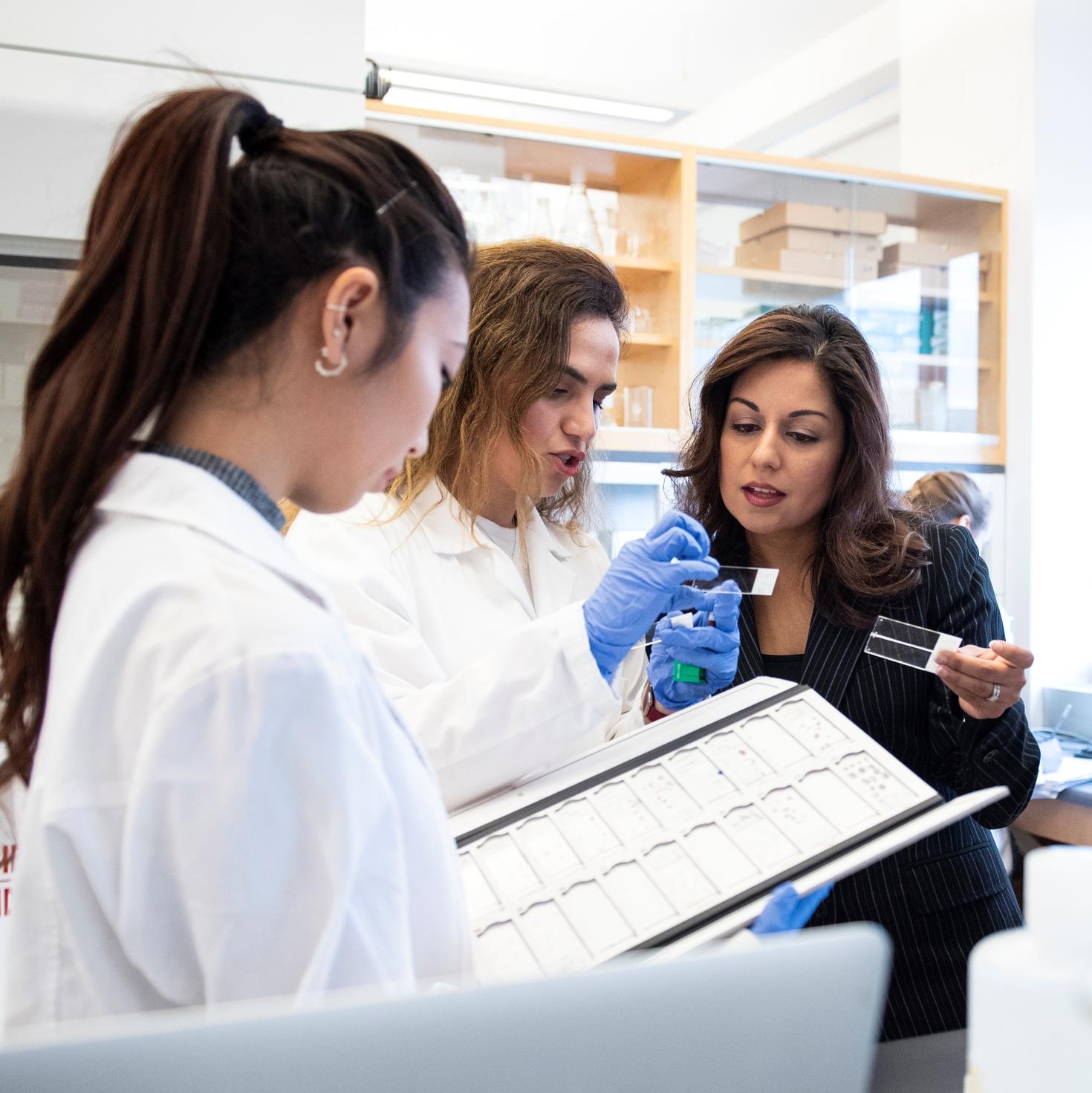 Three researchers, including Dr. Nafissa Ismail, are talking and smiling in a lab.