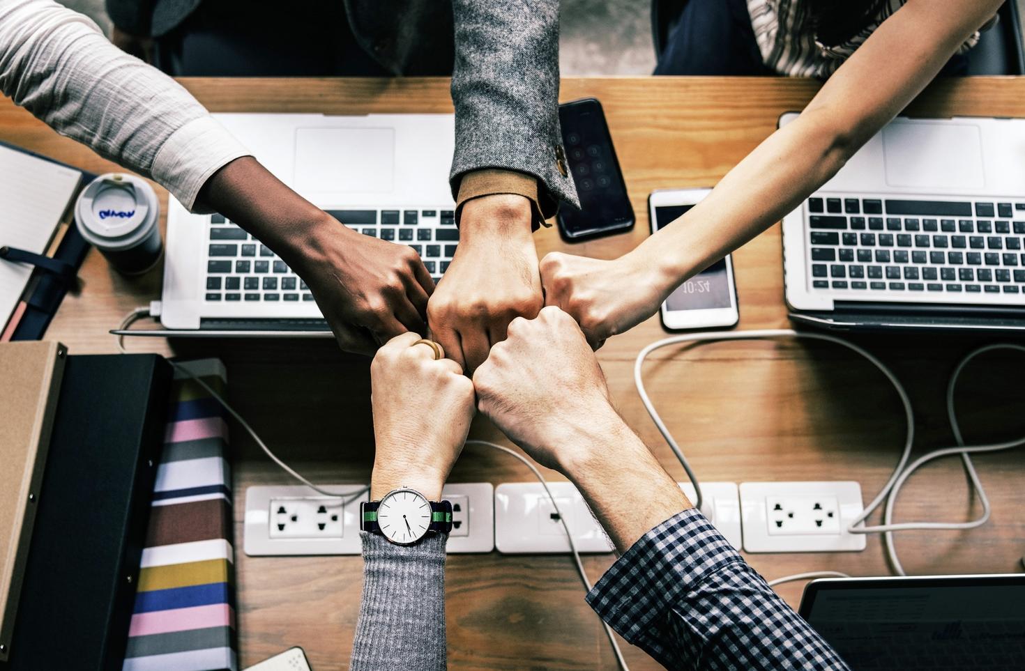 Hands touching over laptop computers showing community.