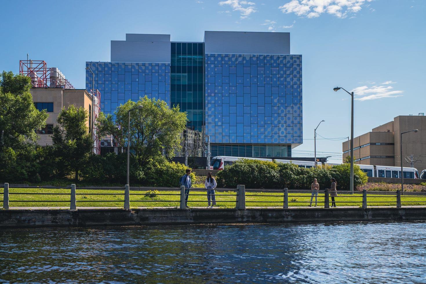 Students by the Rideau canal with STEM complex in the background