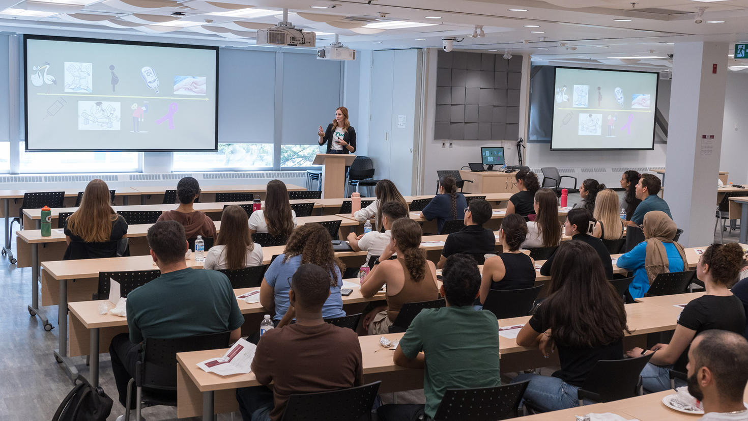 A teacher stands in front of a roomful of medical students