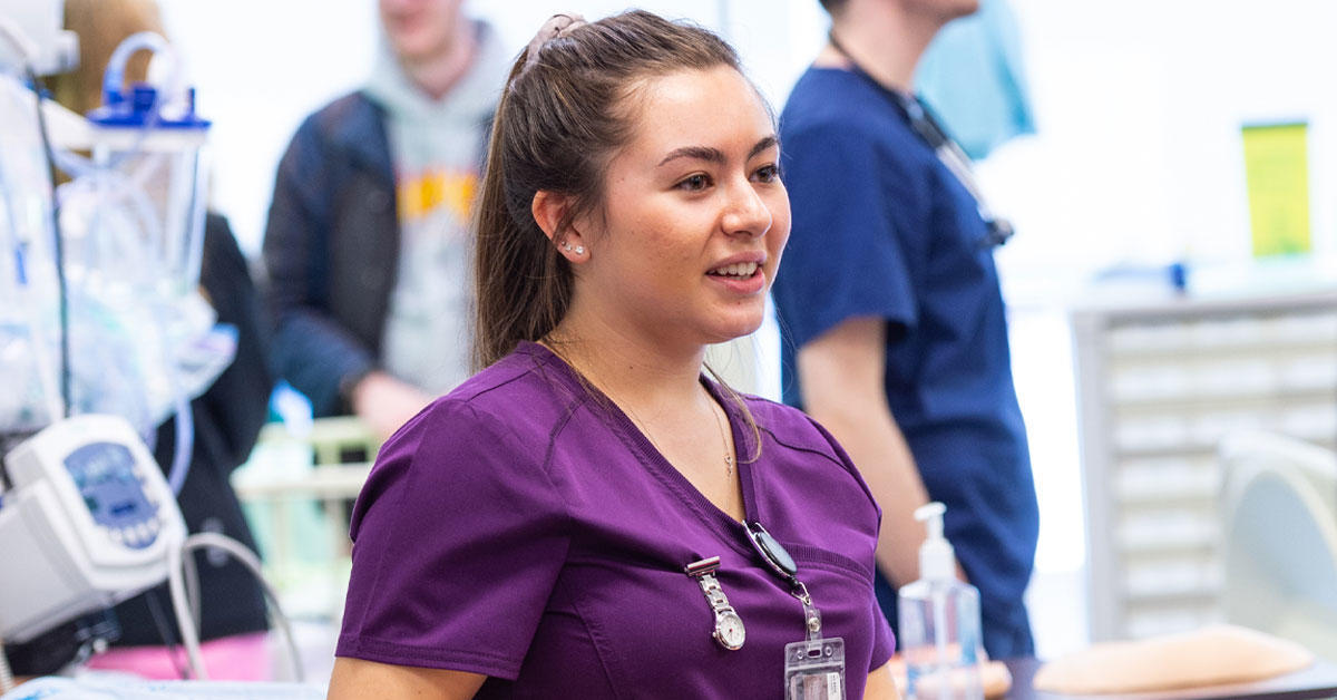 Young woman wearing a nurse's uniform in a medical facility.