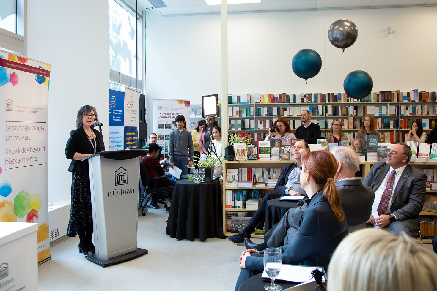 Lara Mainville in front of a podium addressing a group of people at the inauguration of the new premises.