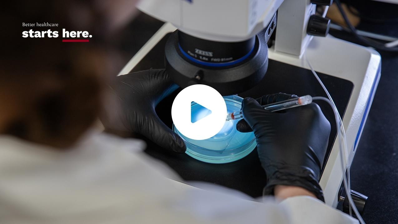 View over the shoulder of a person, looking at a sample looking at a sample under the microscope