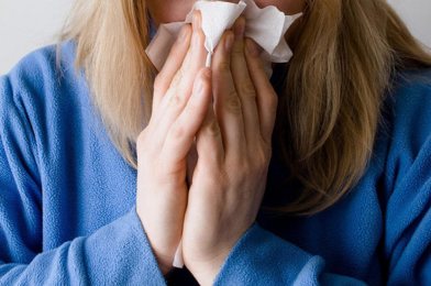 Une femme se mouchant dans un mouchoir.