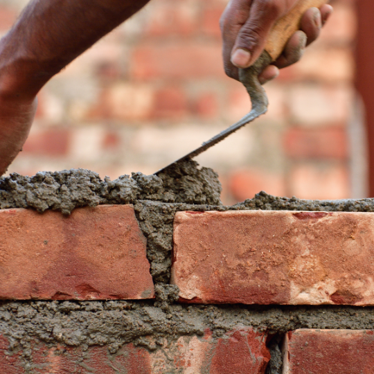 Person adding mortar to brick wall