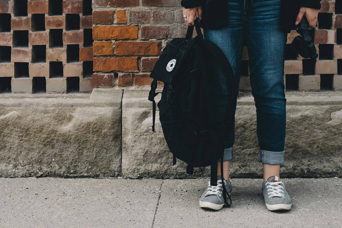 Student holding backpack above the ground