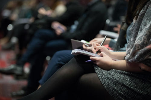 People taking notes while sitting in an auditorium