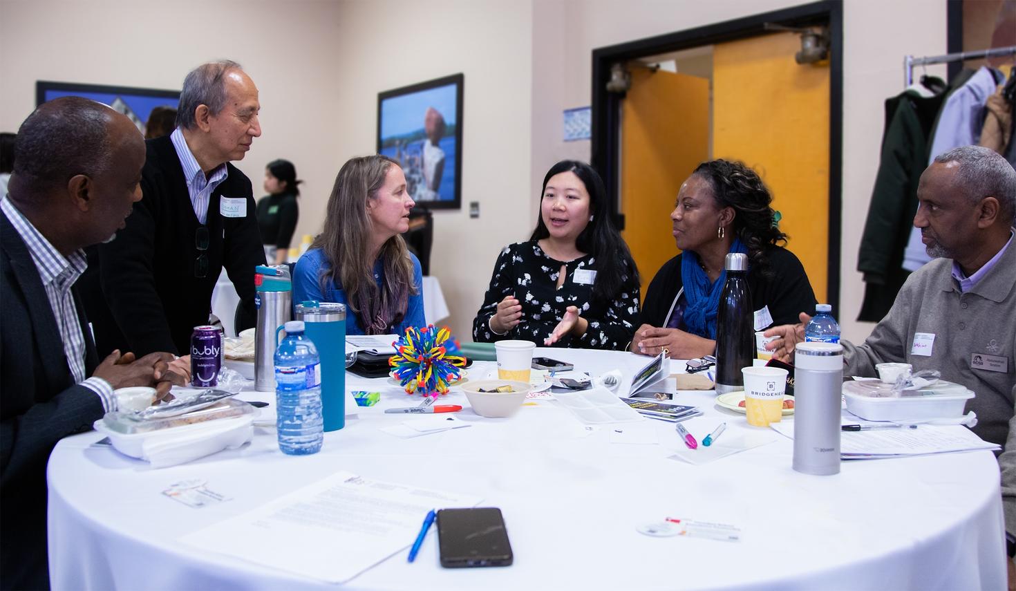 Professor Jess Whitley and members of the Ottawa Community Immigrant Services Organization seated around a table having a discussion.