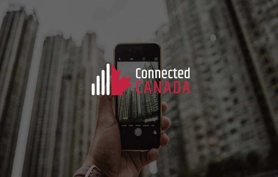 hand holding a cellphone taking a picture of buildings, with the words Connected Canada overlay