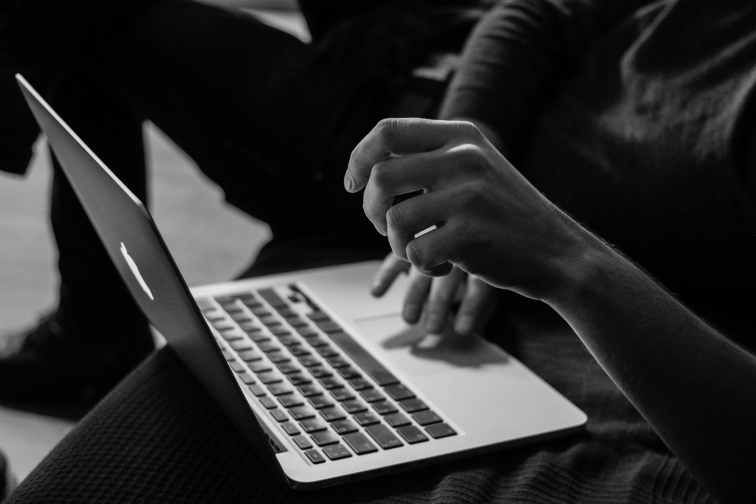 Black and white image of laptop on lap of a woman