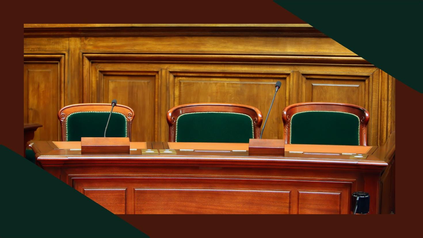 An empty hearing room with wooden paneling and green  chairs.