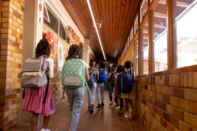 Young students with backpacks walking in school hallway