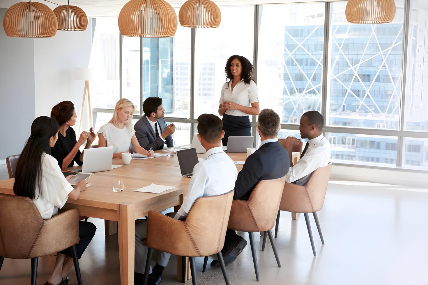 A woman standing and speaking to colleagues during a business meeting in a modern conference room.