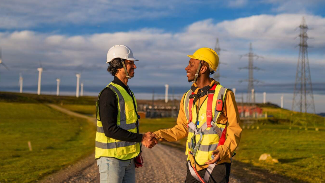Two men shaking hands in windmill field