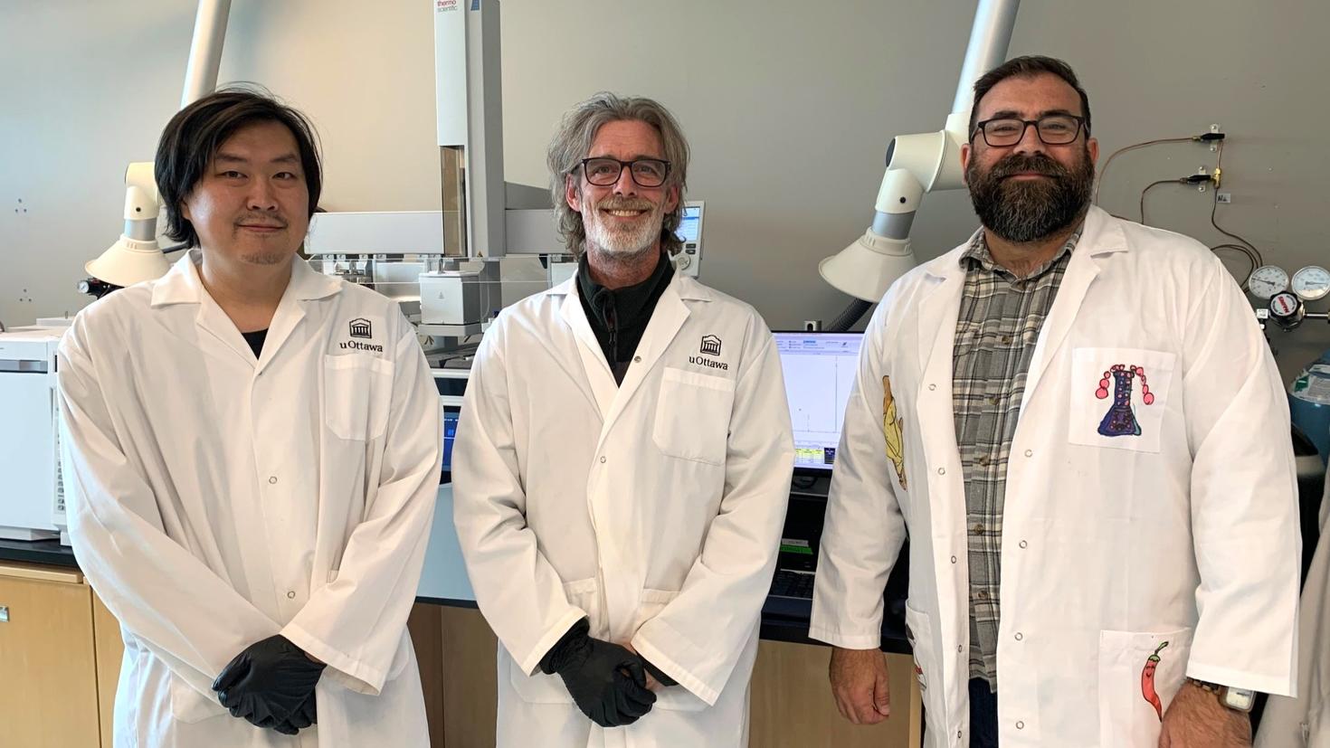 (From left to right) Rui Liu, lab manager and RADAR senior analyst; Professor Cory Harris; and Professor Adam Shuhendler stand in front of lab equipment. All three are in white lab coats.