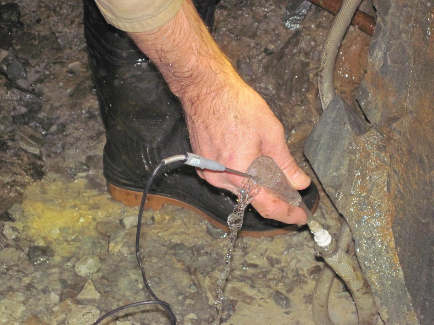 Professor Warr uses a measurement probe to measure the gas bubbles emerging from groundwater.