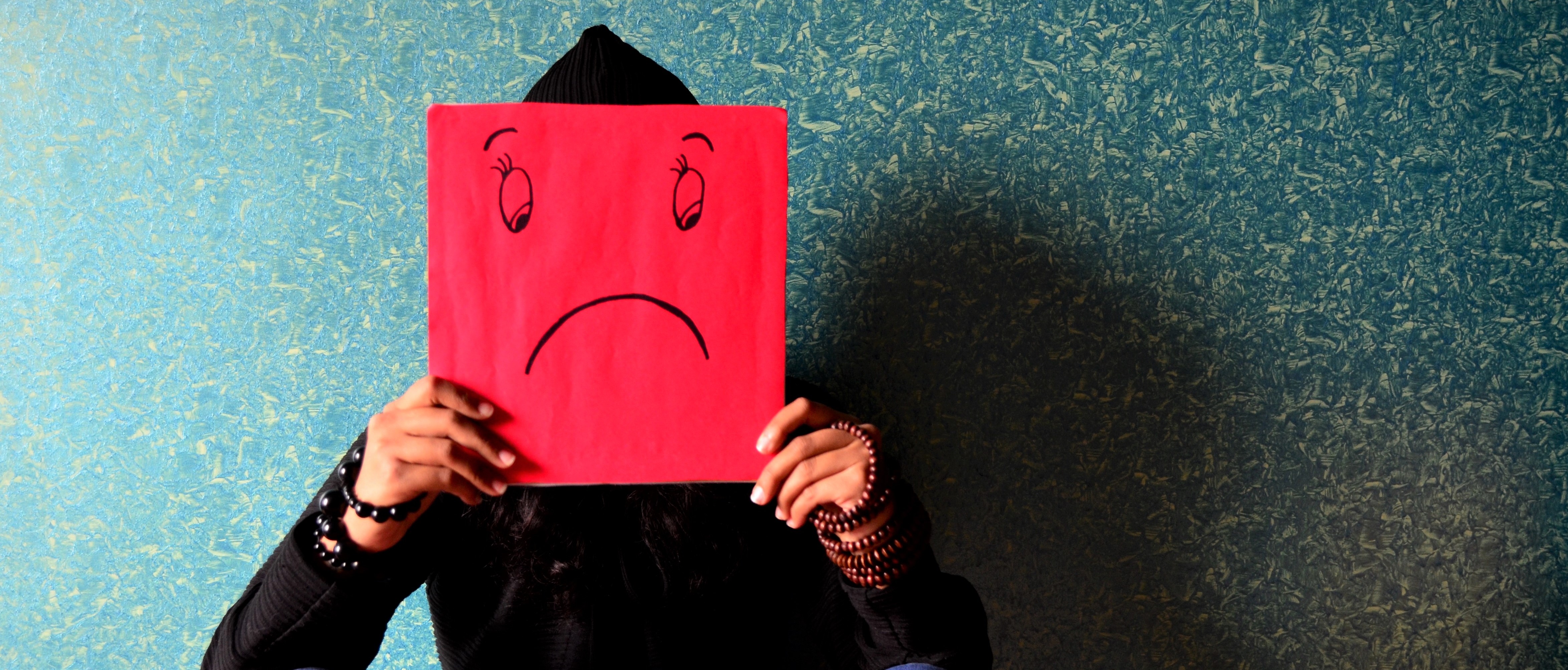 Image d'un adolescent tenant une affiche avec un emoji triste Adolescent exprimant de la tristesse.