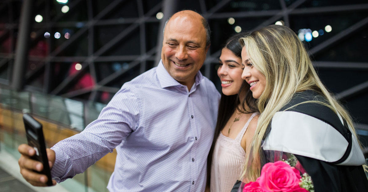 Un père et ses deux filles prennent une photo à la collation des grades