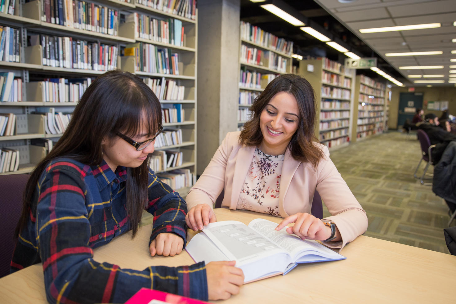 Two students read a book.