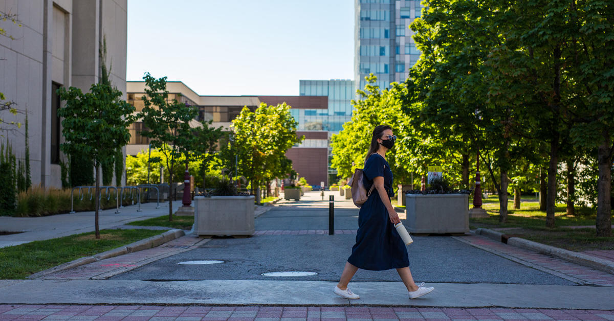 Student wearing a mask walking in an empty campus