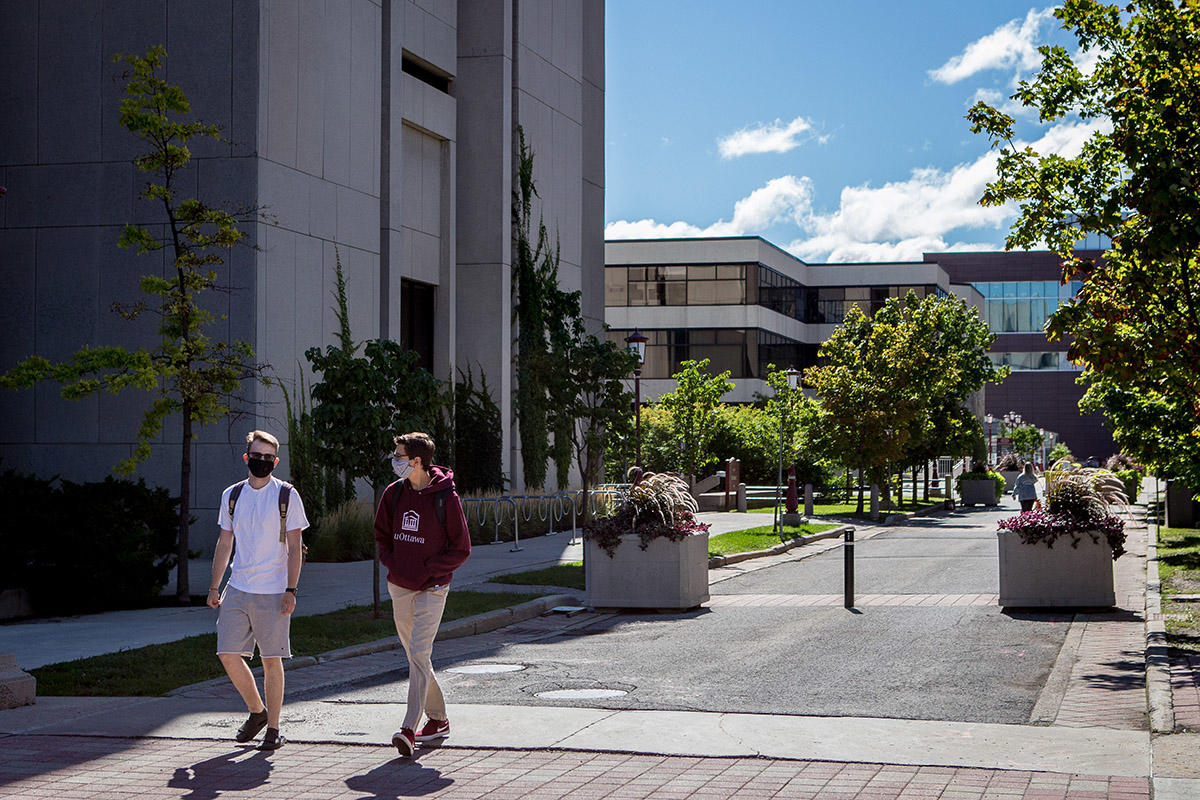 two student walking on campus wearing face masks and socially distant