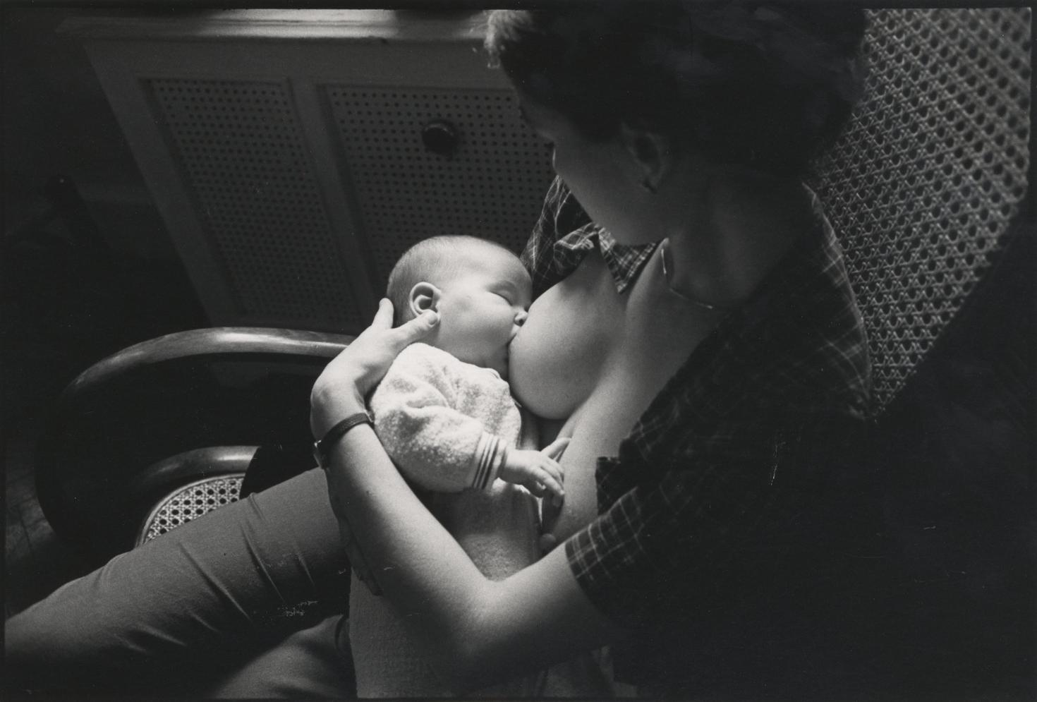 a young woman in a rocking chair, nursing an infant.