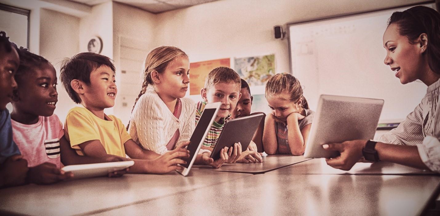 Elementary school kids gathered around teacher with iPads