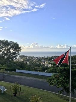 Une route de Trinité-et-Tobago avec le drapeau sur le côté droit et la mer en arrière-plan.
