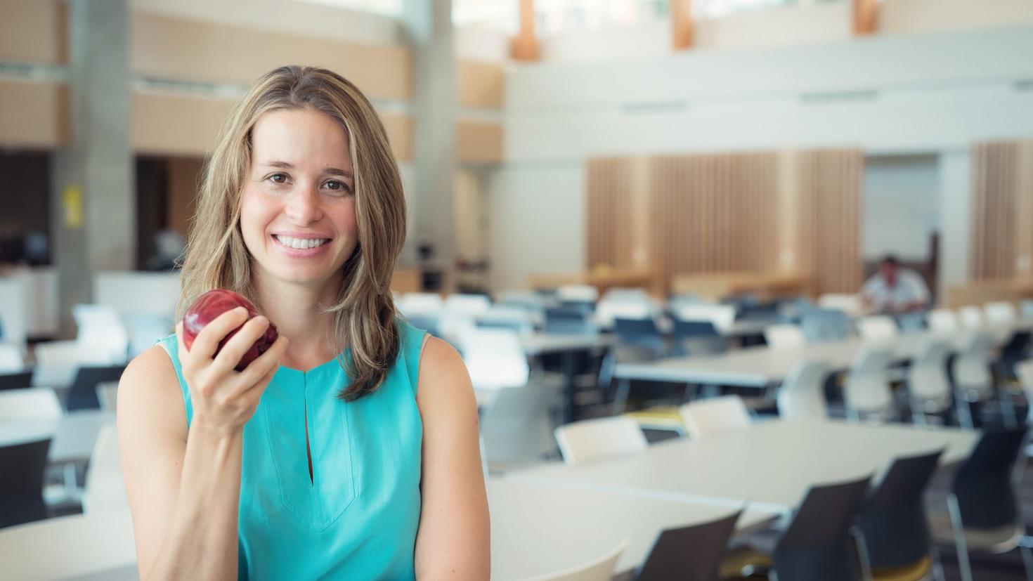 femme sin une salle de conférence souriant et tenant une pomme
