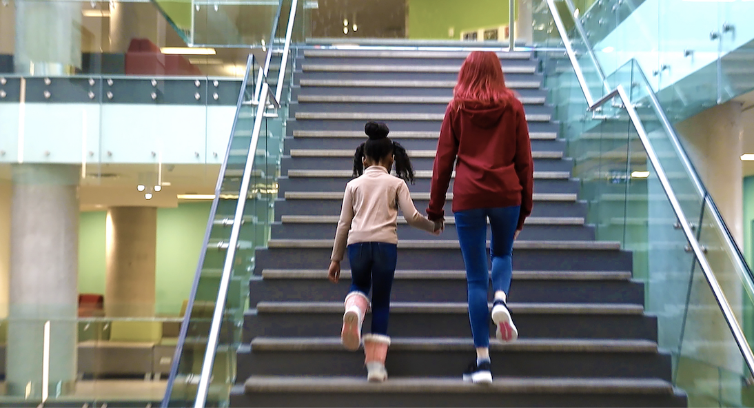 Deux personnes montent un escalier moderne en se tenant par la main.