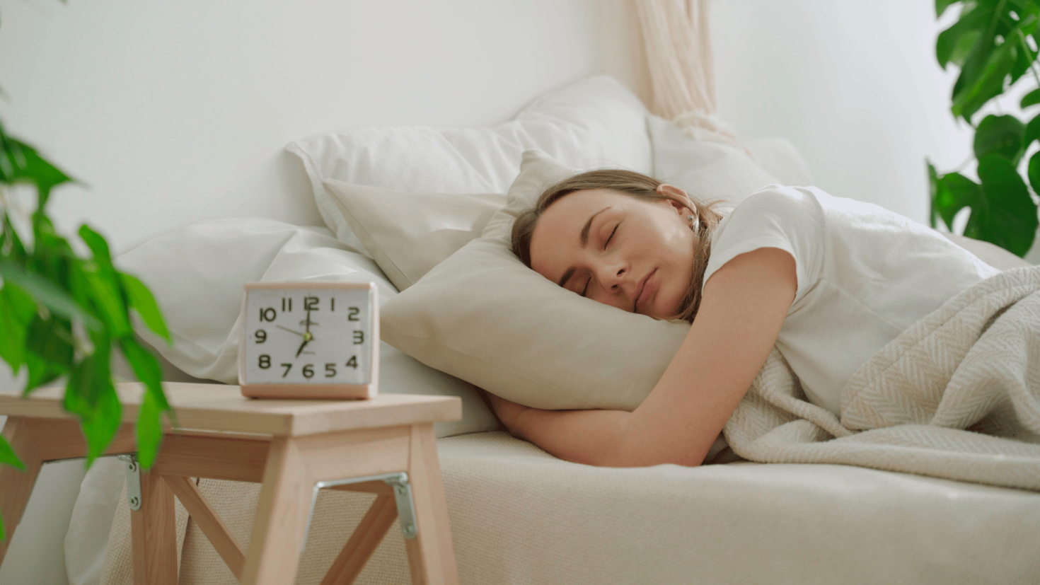 person sleeping in bed clock facing us says 7 o'clock