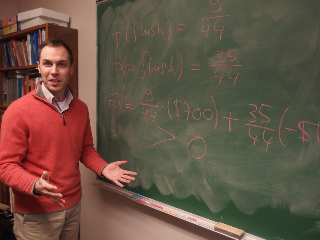 Le professeur Pieter Hofstra, debout devant un tableau sur lequel on peut voir des formules mathématiques relatives à son célèbre cours Poker 101.