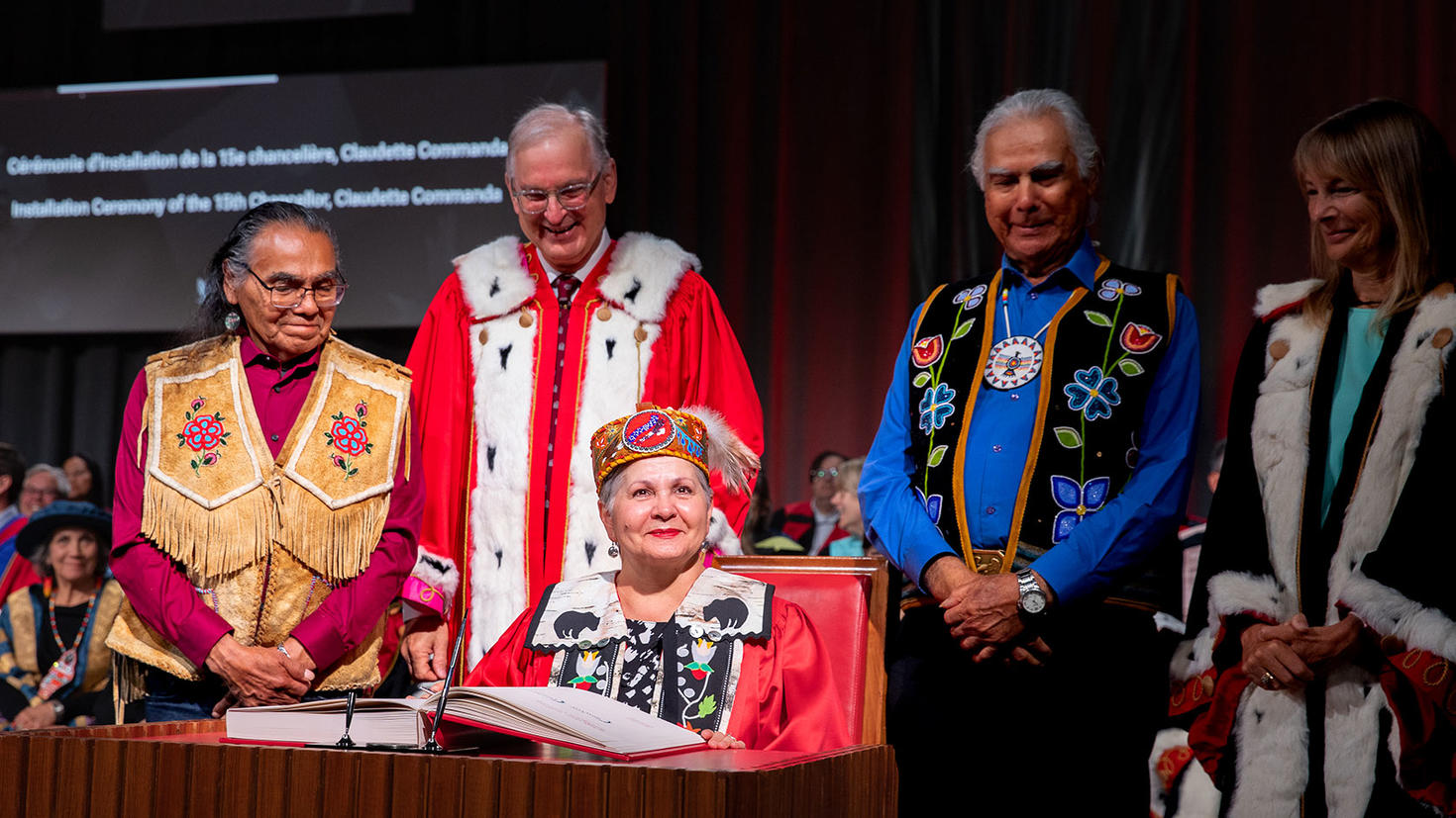 Claudette Commanda, chancelière de l'Université d'Ottawa, signant le livre aux côtés du président Jacques Frémont et des aînés. 