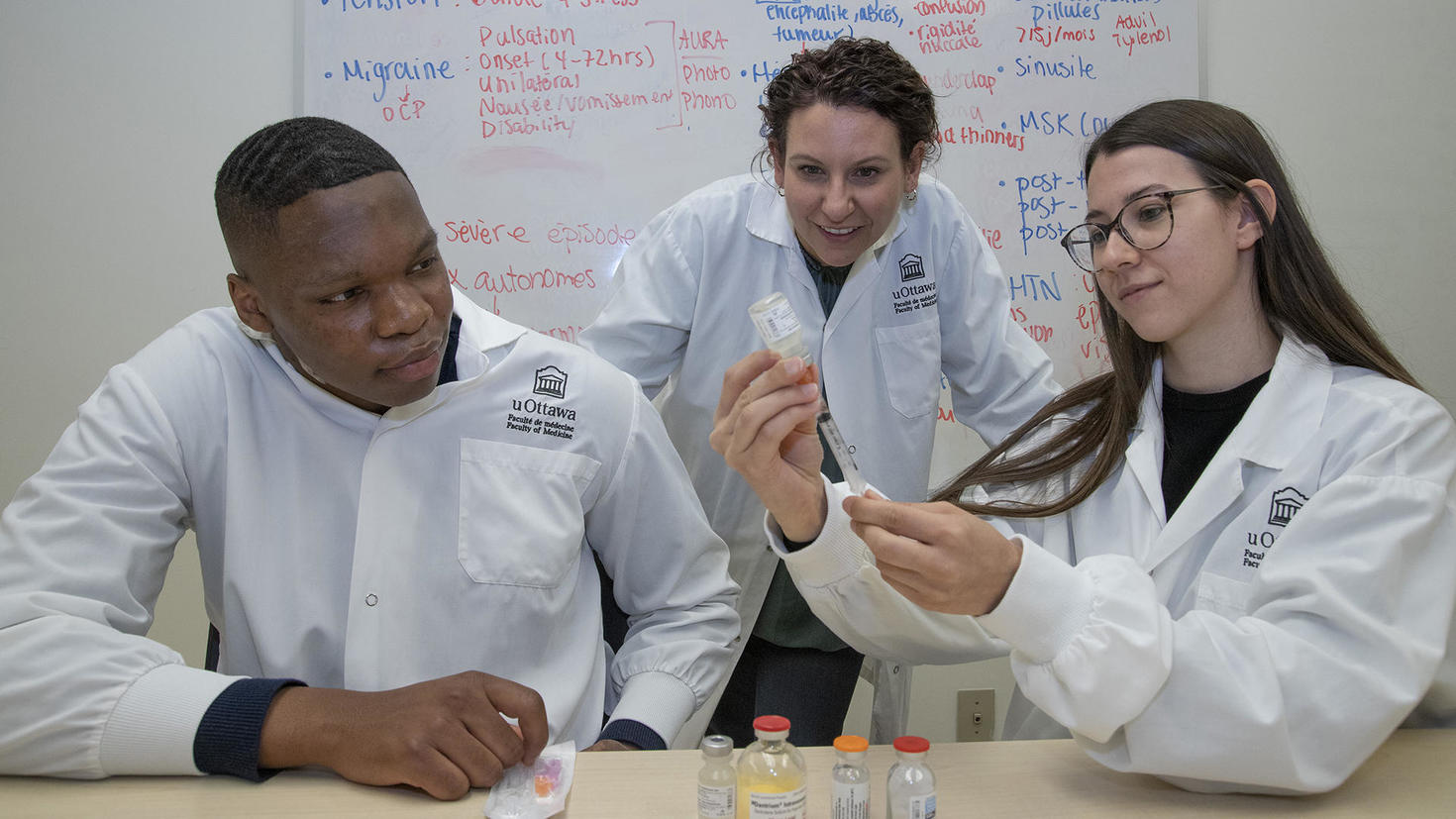 A professor assists two pharmacy students