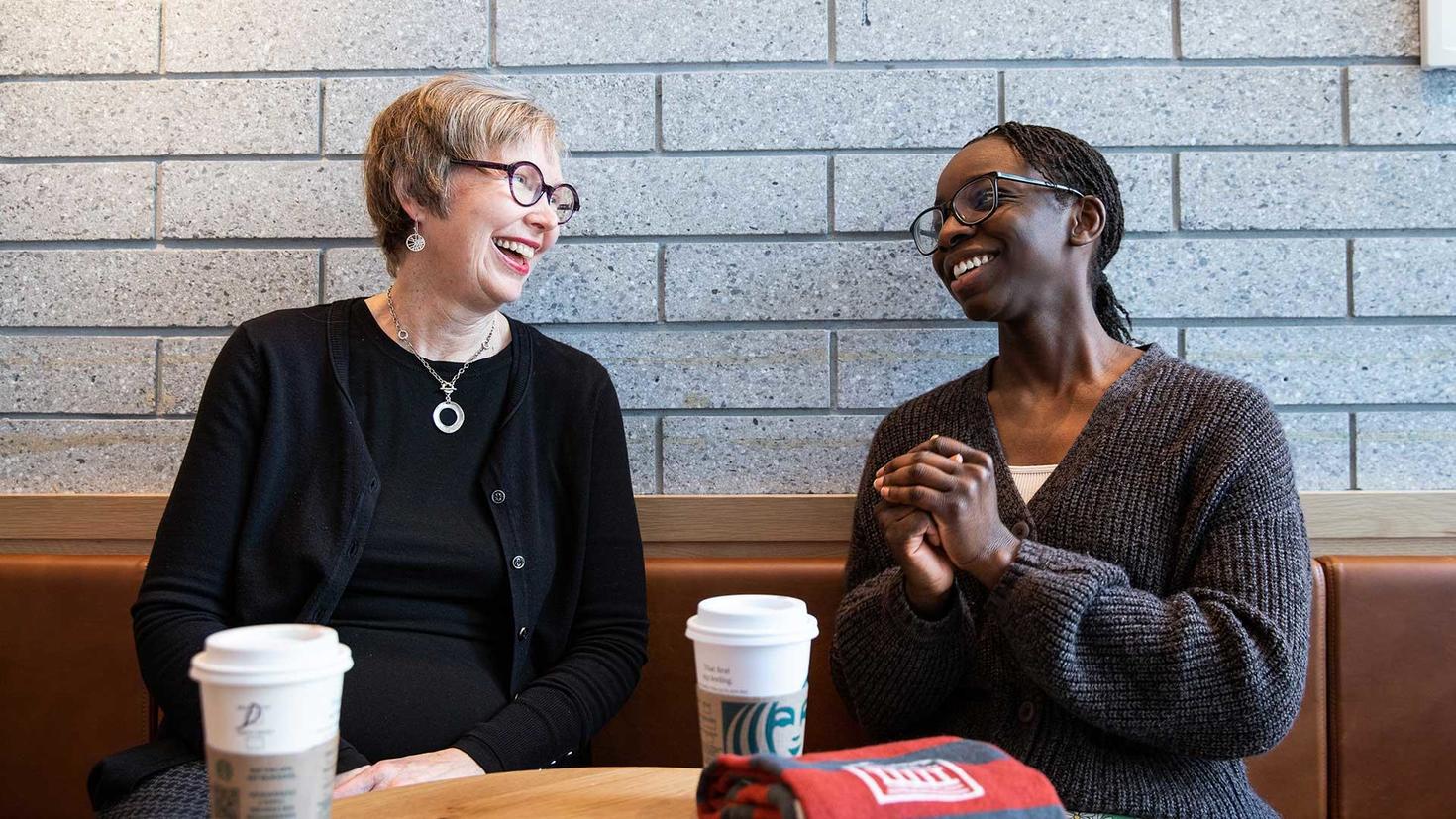 Marlene Patrick et Lily Omakor discutent, souriantes, devant un café.
