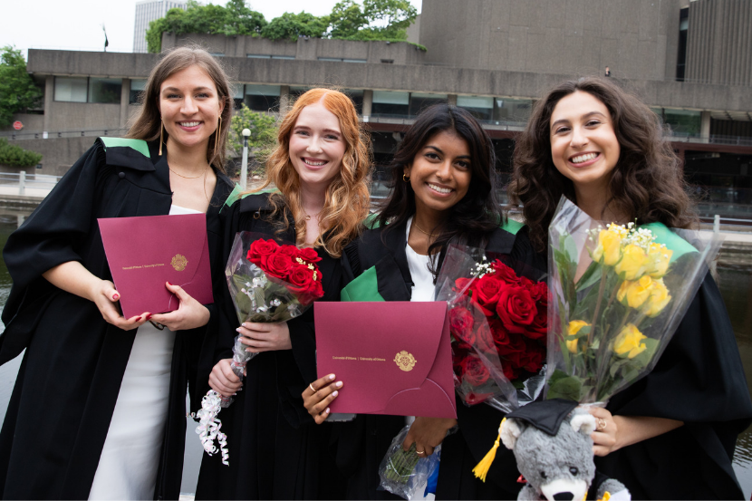  quatre diplômés avec des fleurs et leurs diplômes après la cérémonie