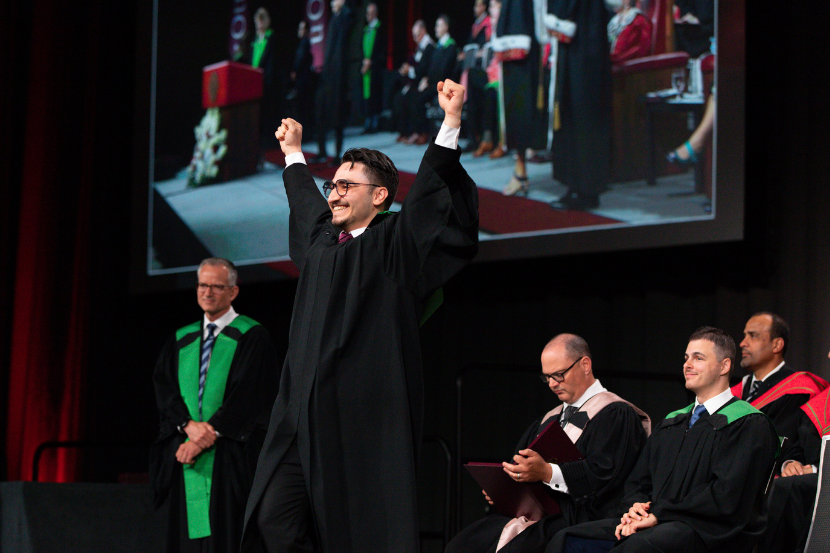 Graduate crossing the stage while cheering