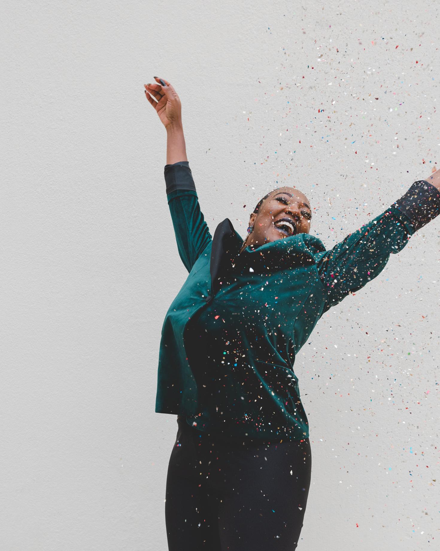 femme avec un manteau vert qui celebre son succes