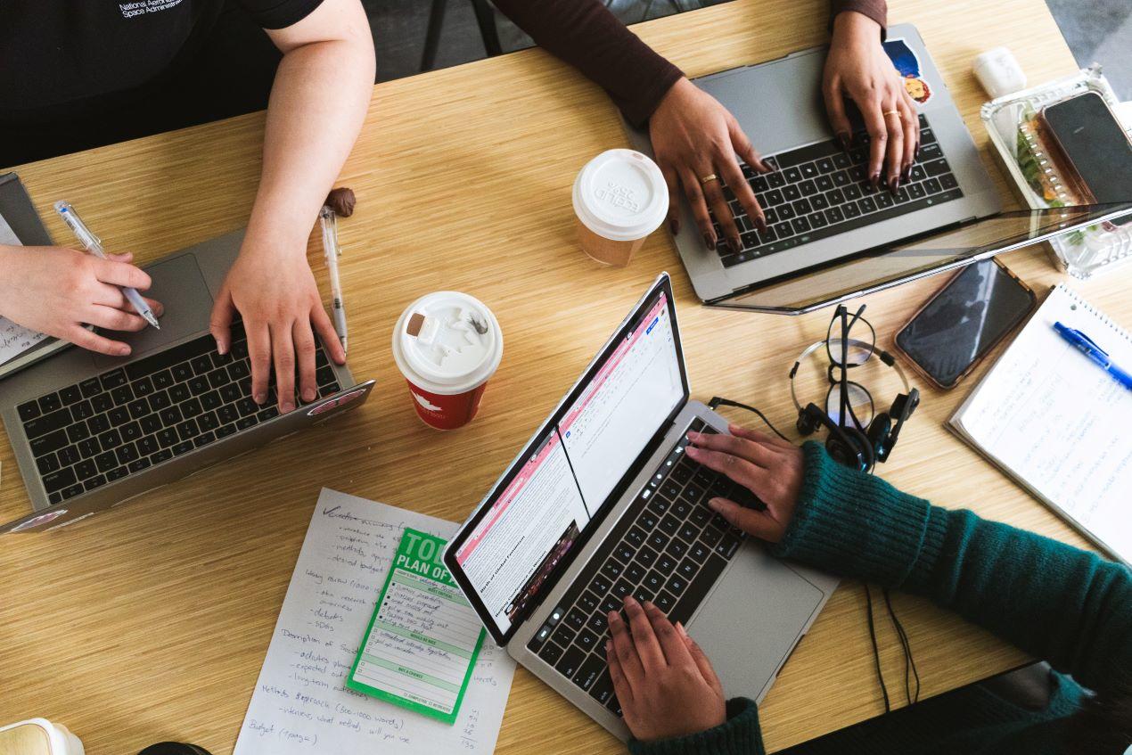 overhead view and close up of three people with their hands on laptop keyboards