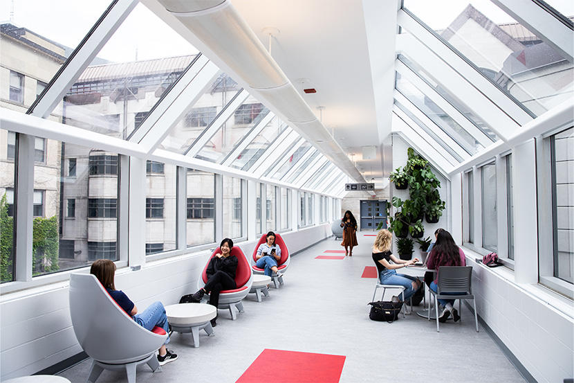 Students studying in the sunshine inside the Hamelin-Simard connecting bridge
