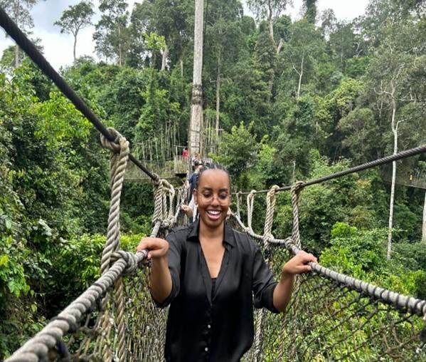 People walking on an hanged bridge in the forest. Forest in the background