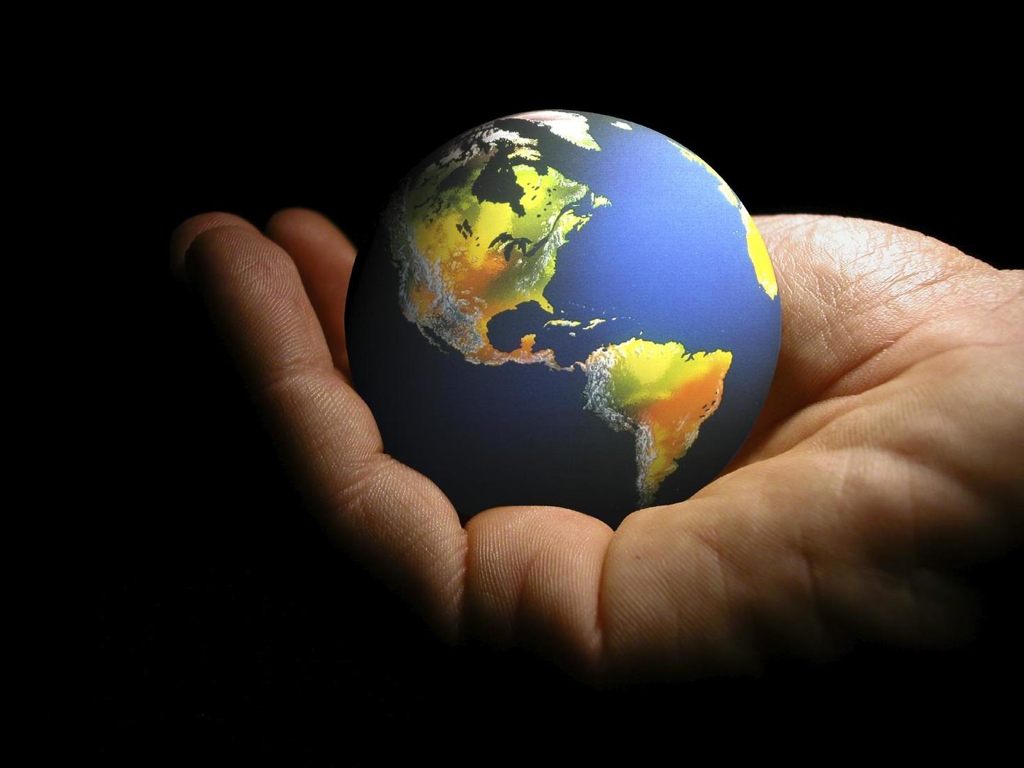 Hand holding a ball in the shape of planet earth