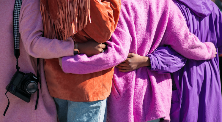 Four women embracing, view from back 