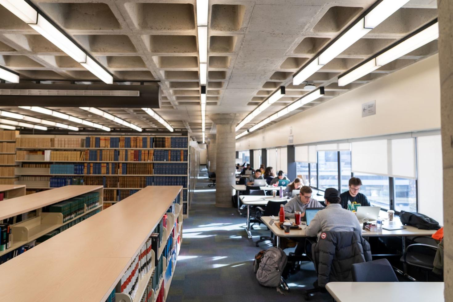 Students studying at tables inside a library. 