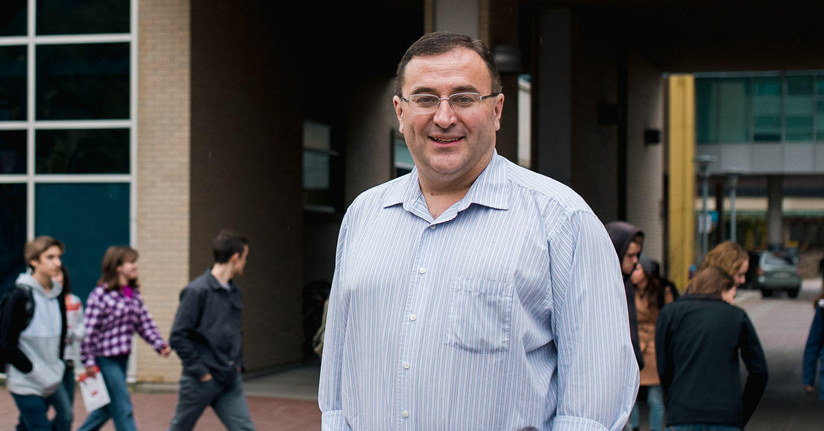 portrait of alain st amant standing in front of biosciences building