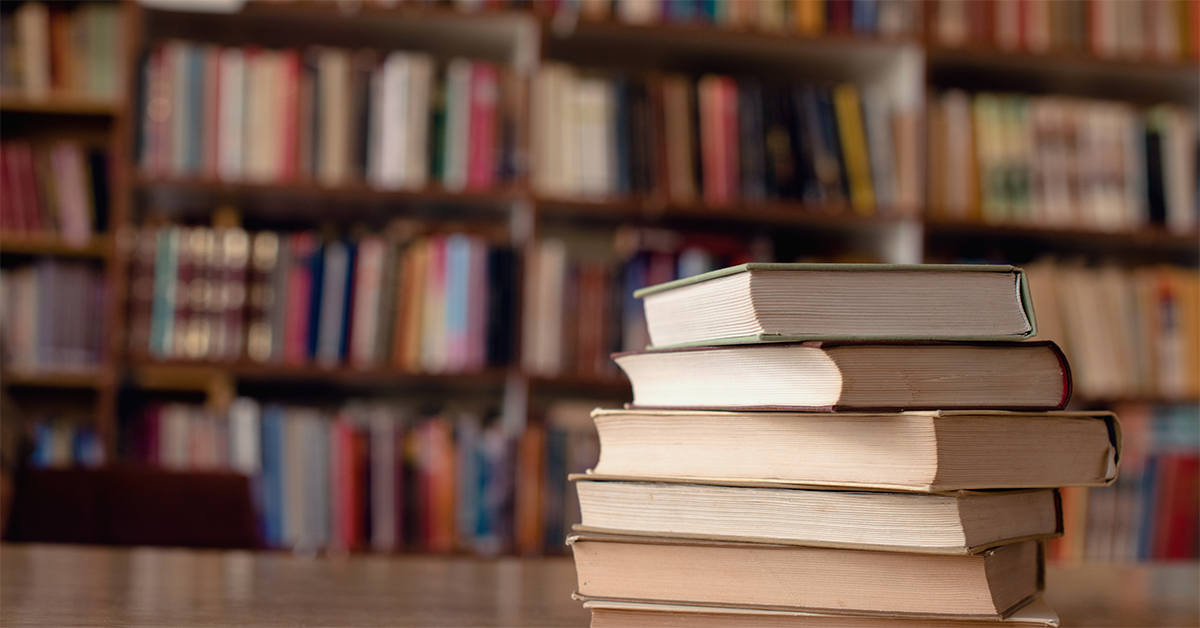 A pile of books on a table in a library.