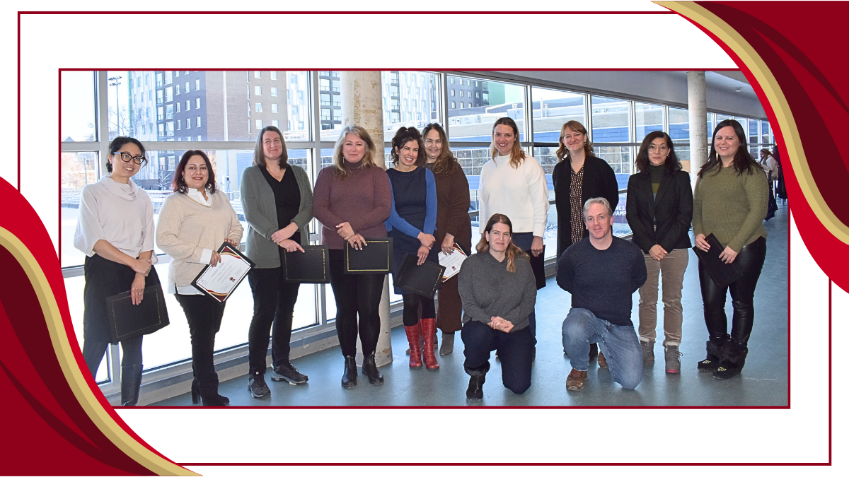 A group of people stand in a line, facing the camera. Many smile. some hold certificates in their hands
